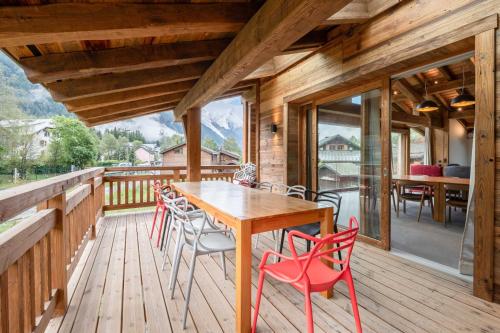une terrasse en bois avec une table et des chaises en bois dans l'établissement Chalets ASA 426 m2, à Chamonix-Mont-Blanc