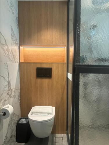 a bathroom with a toilet and a wooden wall at Claude Hotel in Singapore