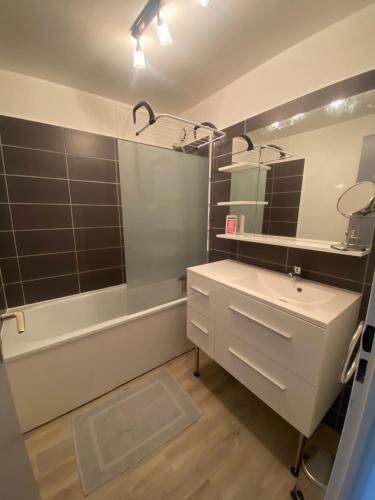 une salle de bain avec un lavabo, une baignoire et un miroir dans l'établissement Studio-Calais Plage-Front de mer, à Calais