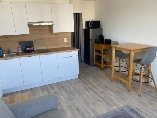 - une cuisine avec des placards blancs, une table et un réfrigérateur dans l'établissement Studio-Calais Plage-Front de mer, à Calais