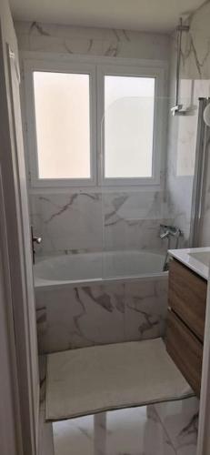 La salle de bains est pourvue d'une baignoire, d'une fenêtre et d'un lavabo. dans l'établissement La Belle Vue d'Auxerre, à Auxerre