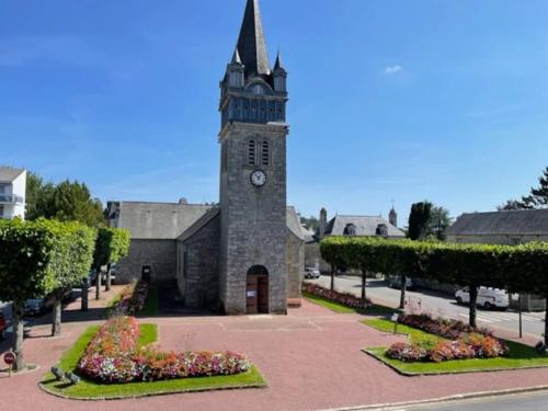 une église avec une tour d'horloge dans une rue dans l'établissement Chalet 1er, bel appartement, à Bagnoles-de-l'Orne