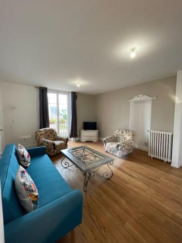 un salon avec un canapé bleu et une table dans l'établissement Chalet 1er, bel appartement, à Bagnoles-de-l'Orne