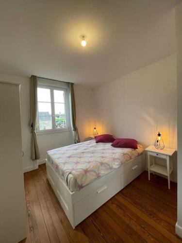 une chambre avec un grand lit et une fenêtre dans l'établissement Chalet 1er, bel appartement, à Bagnoles-de-l'Orne