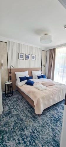 a large bedroom with a large bed with blue pillows at Central Park Mielno Operator Team- apartament IVO in Mielno