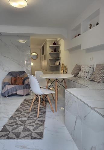 a white kitchen with a table and a bed at Olive Τree Ηouses in Votsalákia