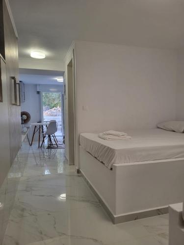 a white bedroom with a bed and a dining room at Olive Τree Ηouses in Votsalákia