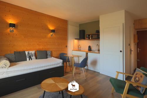 a bedroom with a bed and a table and a kitchen at Le Petit Ours & Le Petit Cerf - Studios vue lac & montagnes in Les Angles