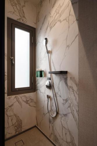 a shower in a bathroom with a marble wall at Claude Hotel in Singapore