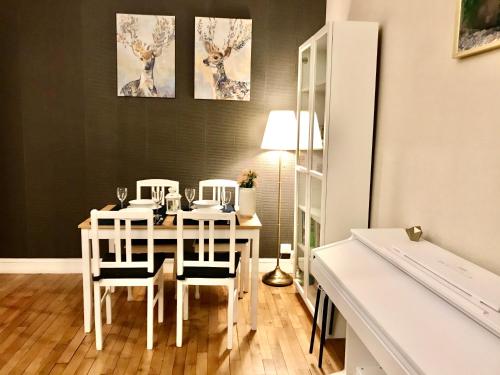 une salle à manger avec une table et des chaises blanches dans l'établissement Appartement près de Paris 14ème, à Arcueil