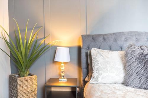 a bedroom with a bed with a lamp and a plant at Luxury townhouse in Workington in Workington