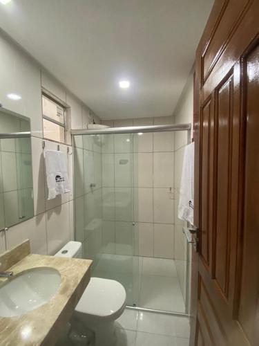 a bathroom with a shower and a toilet and a sink at Hotel Beira do Rio in Ibotirama