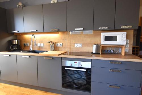 une cuisine avec une cuisinière et un micro-ondes dans l'établissement VAUJANYLOCATIONS - Amethystes B3, à Vaujany