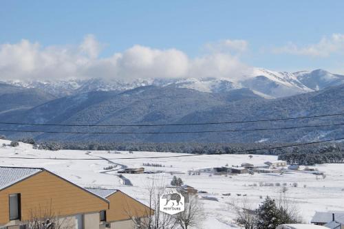 a snow covered field with mountains in the background at Le Petit Ours & Le Petit Cerf - Studios vue lac & montagnes in Les Angles