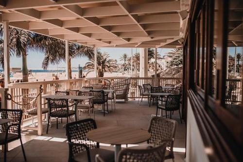 a restaurant with tables and chairs and the beach at MY SEA VIEW HOLIDAY APARTMENT in Maspalomas