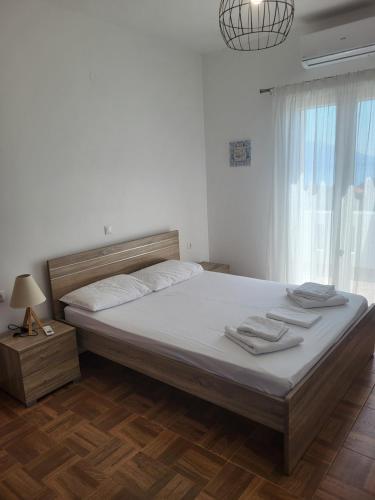 a bedroom with a bed with white sheets and a window at Olive Τree Ηouses in Votsalákia