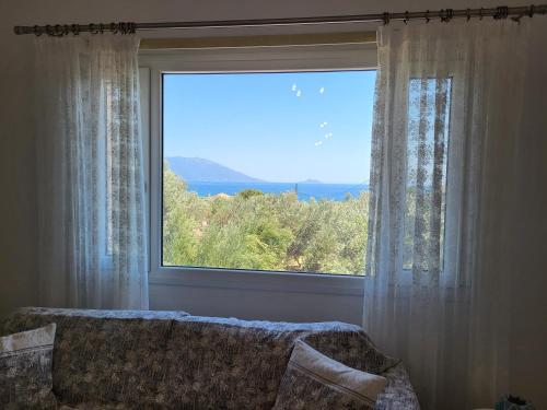 a large window with a couch in front of it at Olive Τree Ηouses in Votsalákia