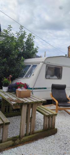 a white rv parked next to a wooden table and a picnic table with at Luxury house in Coldingham