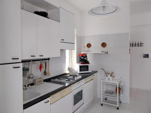 Una cocina blanca con estufa y fregadero. en Casa Re di Picche, en San Nicola Arcella