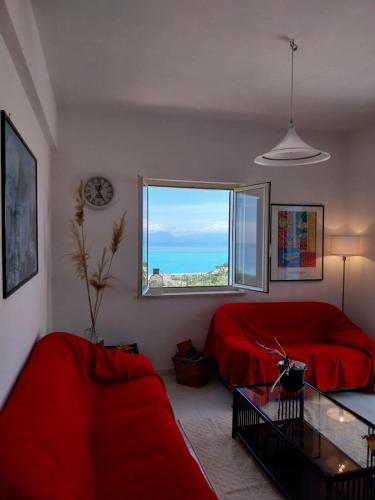 a living room with a red couch and a window at Casa Re di Picche in San Nicola Arcella