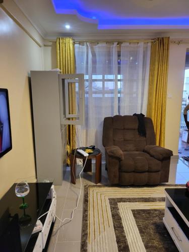 a living room with a brown chair and a tv at G&G Homes Pioneer 1 bedroom in Eldoret