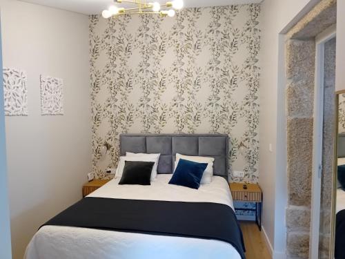 a bedroom with a large bed with blue pillows at Quinta dos Tojais Hotel Rural in Celorico de Basto