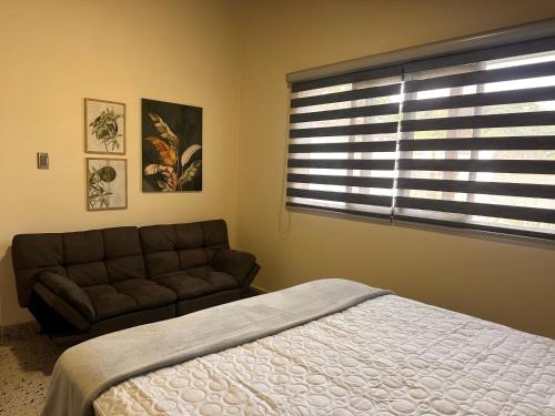 a bedroom with a bed and a couch and a window at Magiko Suites in Roldanillo