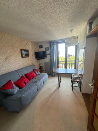 un salon avec un canapé bleu avec des coussins rouges dans l'établissement La Reine des Neiges au Clematite, à Risoul