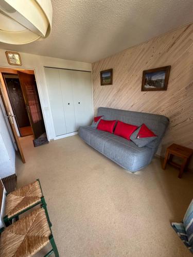 un salon avec un canapé gris avec des coussins rouges dans l'établissement La Reine des Neiges au Clematite, à Risoul