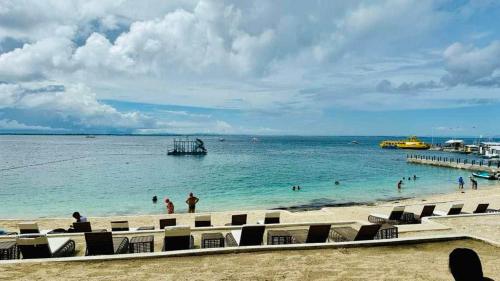 a beach with people in the water and a pier at Budget friendly 1bedroom in The Mactan Newtown with pool&beach access in Punta Engaño