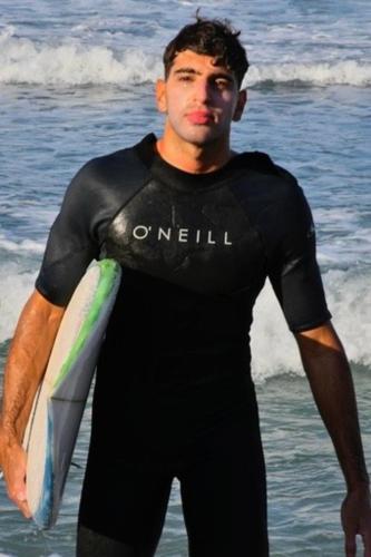 a man in a wet suit holding a surfboard at Aloe & Lotus Villas in Prinés