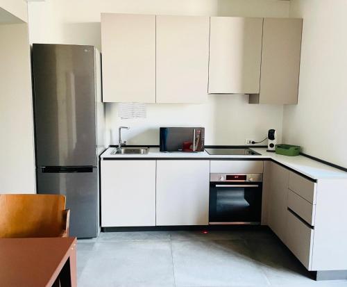 a kitchen with white cabinets and a stainless steel refrigerator at STADLERINO - Tiny Loft in Venice in Marghera
