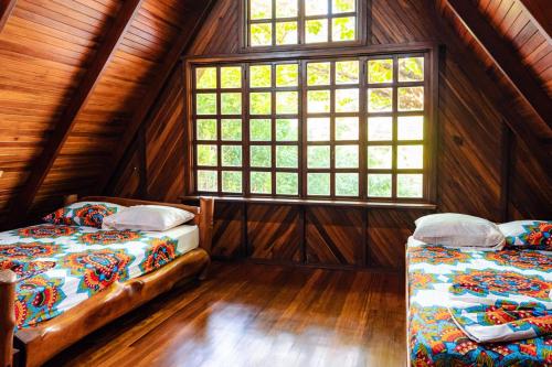 two beds in a room with a window at FLOR DE PARAISO BUNGALOWS in Montezuma