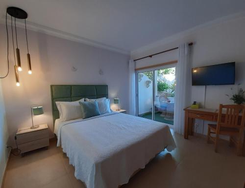a bedroom with a bed and a desk and a window at Lucie Lime GuestHouse in Luz