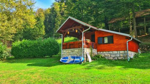 a house with a porch and a boat in front of it at Holiday Home Radočaj in Slunj