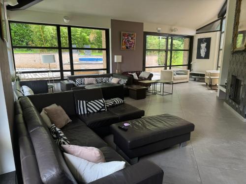 a living room with couches and tables and windows at Villa des Templiers - 20 min Brussels Airport in Wavre