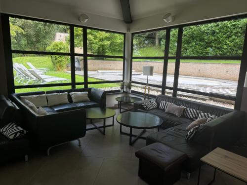 a living room with couches and tables and large windows at Villa des Templiers - 20 min Brussels Airport in Wavre