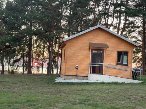 a small wooden building in a field with trees at Rāznas ezera namiņš D1 ar elektrisko apkuri in Ragi