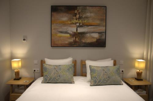 a bedroom with a bed with two lamps and a painting at Villa Isobel in Vila Verde