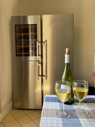 a bottle of wine and two wine glasses on a table at Maison de Famille Les Tourelles in Tour-de-Faure
