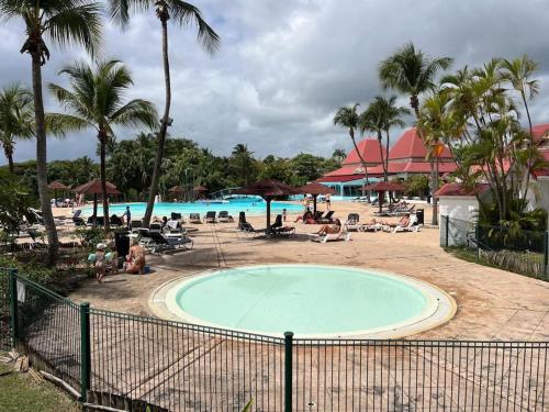 a large swimming pool with people sitting around it at Studio Ti Gwama Village Vacances in Sainte-Anne