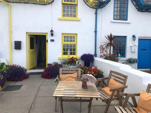 a wooden table and chairs in front of a house at Promenade Cottage, Newcastle, County Down in Widows Row