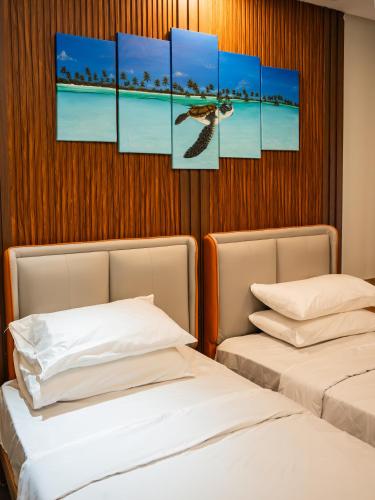 two beds in a room with paintings on the wall at La Pearl Mathiveri in Mathiveri