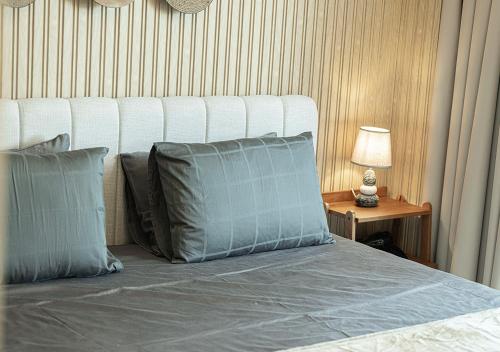 a bed with two pillows and a lamp on a table at Private Platinum Studio Apartment in Al Zahia, Sharjah in Ḩiz̧āyib az Zānah