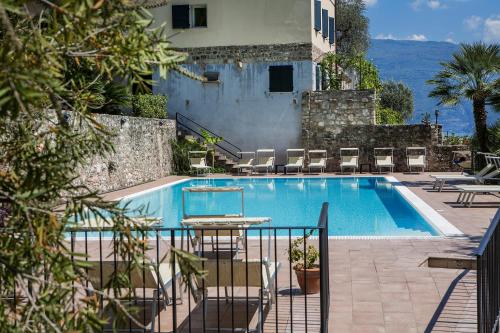 a swimming pool with tables and chairs next to a building at Appartamenti Livia in Gargnano
