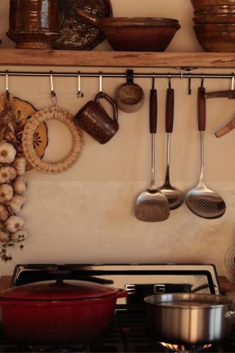 a kitchen with utensils hanging on a wall above a stove at Casa Pauseto in Bonnieux