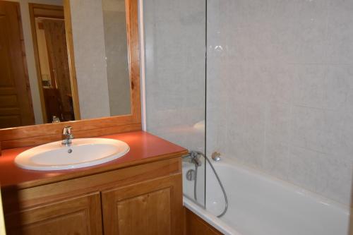 La salle de bains est pourvue d'un lavabo et d'une baignoire avec un miroir. dans l'établissement VAUJANYLOCATIONS - Les Valmonts, à Vaujany