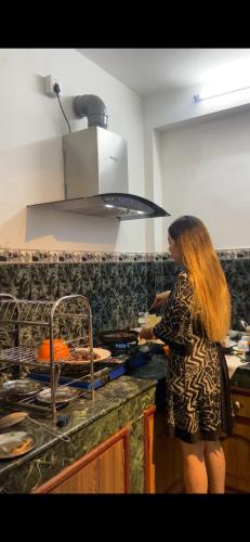 a woman standing in a kitchen preparing food at Apartment at KTM in Bālāju