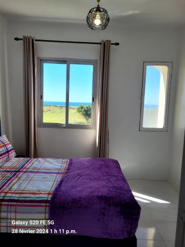 a bedroom with a bed and a window with the ocean at Cosy appartement sur la plage in Jbila