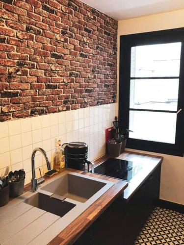 - une cuisine avec un évier et un mur en briques dans l'établissement Superbe appartement T3 dans l'hyper centre, à Blois